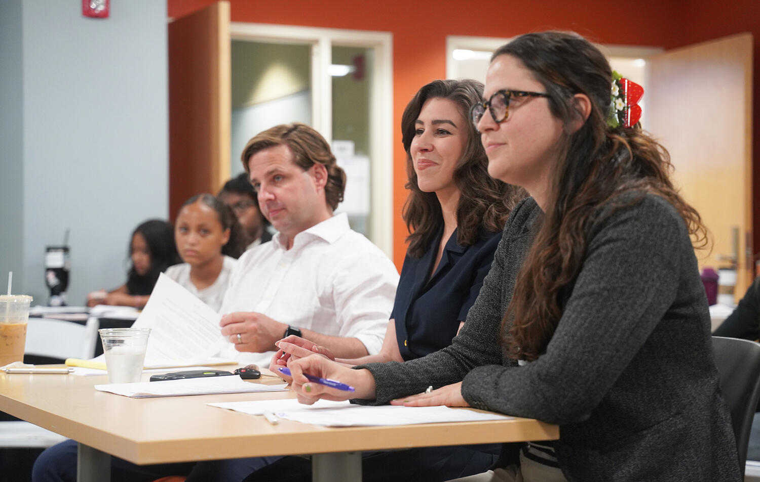 Moderator Kim Kalunian, center, and panelists John Meara and Carla Aveledo listen intently as students present their arguments.