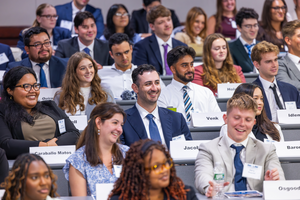 Law students at orientations smiling while inside the courtroom-auditorium seating style event venue
