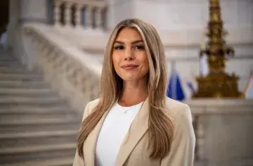 Medium shot of Camille with courthouse steps in the background.