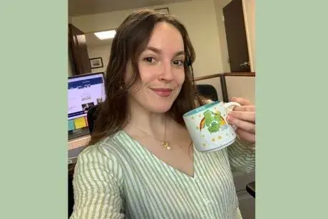Alex Ward holding a green Care Bear coffee cup