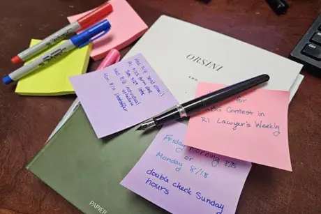 Stacks of papers, sticky note pads, and  pens on a flat surface