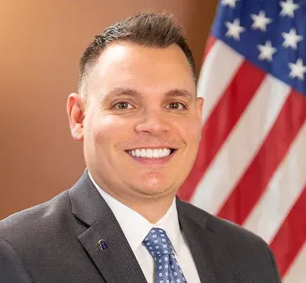 Close up shot of a man wearing a suit with flag in the background