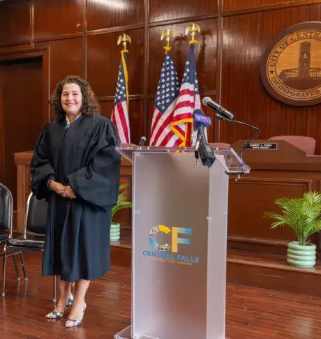 Deborah Gonzales wearing judicial robe in court with US flags behind her