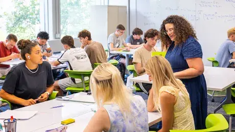 Professor checks on a student's work during class.