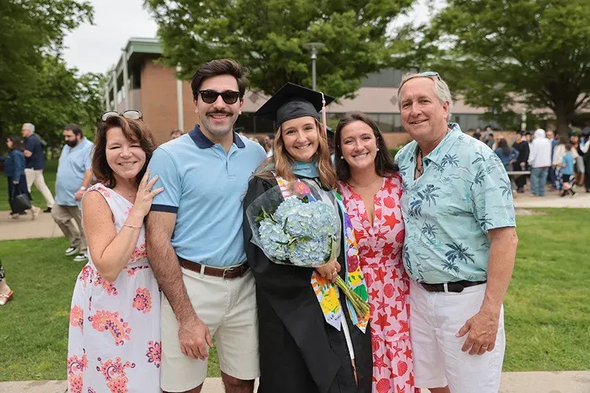 An RWU gradate poses for a photo with family